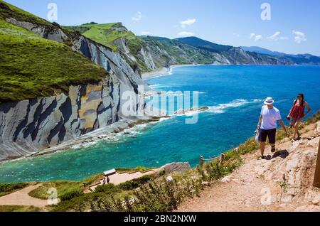 Zumaia, Gipuzkoa, Baskenland, Spanien - 15. Juli 2019 : Touristen wandern auf der Klippe aus Flysch-Felsen. Stockfoto