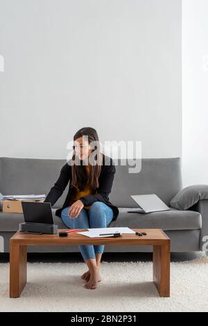 Junge Frau, die zu Hause arbeitet und eine Videokonferenz für Unternehmen zu Hause hat Stockfoto
