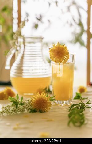 Zitrusfrüchte in einem Glas und einem Krug zwischen den Blumen auf dem Tisch, heller sonniger Morgen Stockfoto