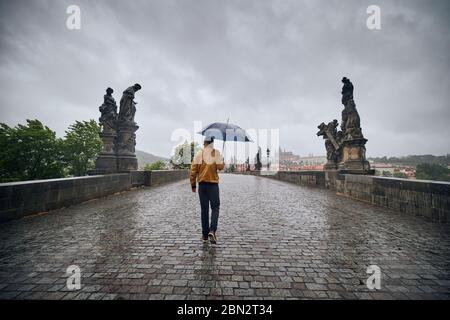 Einsamer Mann mit Regenschirm bei starkem Regen auf der leeren Karlsbrücke. Prag Tschechische Republik Stockfoto