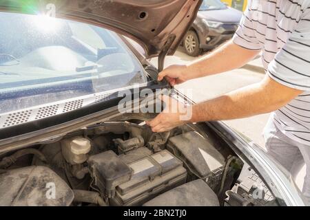 In der Garage arbeitet der Automechaniker. Reparaturen. Entfernen der Kunststoffabdeckung zur Reparatur des Trapezes Stockfoto