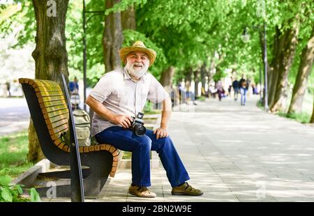 Konzept der Fotografie. Senior bärtigen Mann fotografieren im Freien. Professionelle Fotograf Designer. Glücklich Ruhestand. Alter Mann entspannen auf Bank. Mann Touristen verwenden Kamera Foto machen. Stockfoto