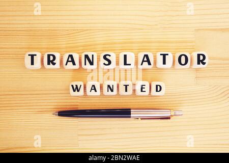 Holzwürfel mit Text Übersetzer gesucht und ein Stift auf Holzhintergrund. Konzept des Personalmanagements, der Personalbeschaffung und der Einstellung. Stockfoto