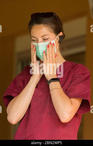 Ein Tierarzt bedeckt ihr Gesicht mit einer medizinischen Maske während einer Tierpflege zu Hause Stockfoto