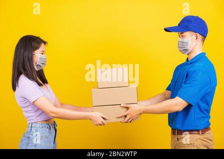 Asiatische schöne Frau und schönen Mann trägt Schutz Gesichtsmaske gegen Coronavirus, Annahme Lieferkartons, Studio auf gelben Rücken isoliert erschossen Stockfoto