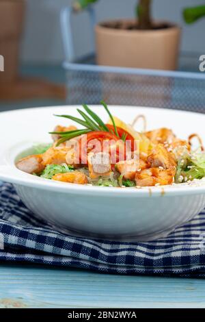 Reisnudeln mit Lachs und Spinat. Mittagessen in einem weißen Teller auf dem Tisch. Tomaten, Zitrone, Fisch, Rosmarin, Soi und Sesam. Stillleben im Essen Stockfoto