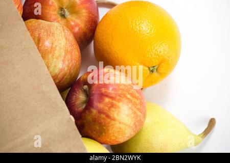 Äpfel und Birnen in einem Papiertütchen Bastelpapier auf weißem Hintergrund. Freier Platz für Ihren Text. Draufsicht. Stockfoto
