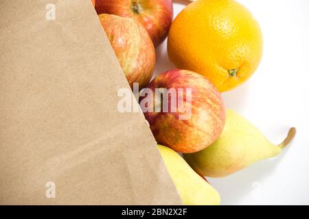 Äpfel und Birnen in einem Papiertütchen Bastelpapier auf weißem Hintergrund Stockfoto
