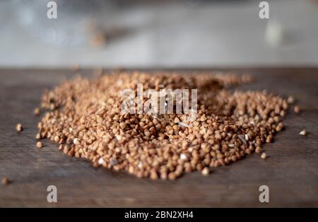 Bild mit weichem Fokus von winzigen korken Glas mit Buchweizen auf dunklem Hintergrund aus verstreuten Buchweizen. Stockfoto