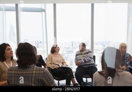 Geschäftsleute, die im Kreis in einem Konferenzraum sprechen Stockfoto