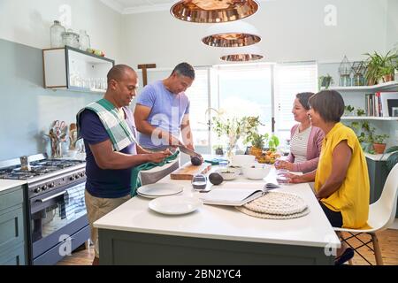 Ältere Ehefrauen beobachten Ehemänner kochen in der Küche Stockfoto
