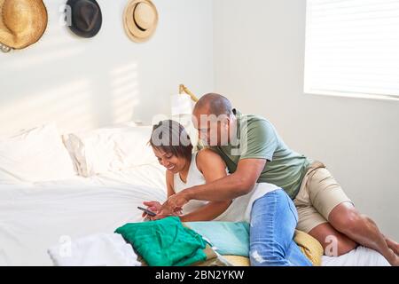 Paar mit Smartphone auf dem Bett Stockfoto