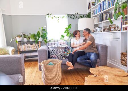 Liebevolle ältere Paar Wäsche auf Wohnzimmer Sofa tun Stockfoto