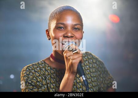 Portrait glücklich junge Musikerin singt ins Mikrofon Stockfoto