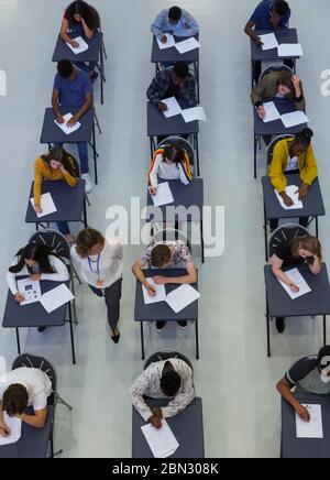 High School Lehrer beaufsichtigt Schüler, die Prüfung an Schreibtischen Stockfoto