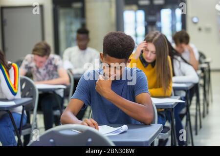 Fokussierte High School Jungen Schüler, die Prüfung am Schreibtisch im Klassenzimmer Stockfoto