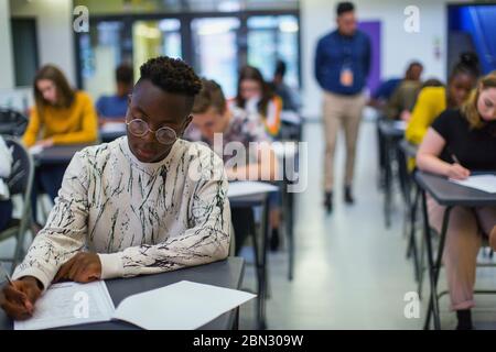 Fokussierte High School Jungen Schüler, die Prüfung am Schreibtisch Stockfoto