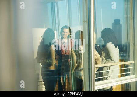 Geschäftsleute, die sich im sonnigen Bürofenster unterhalten Stockfoto