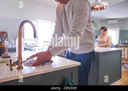 Mann, der Geschirr in der Spüle der Küche abspült Stockfoto