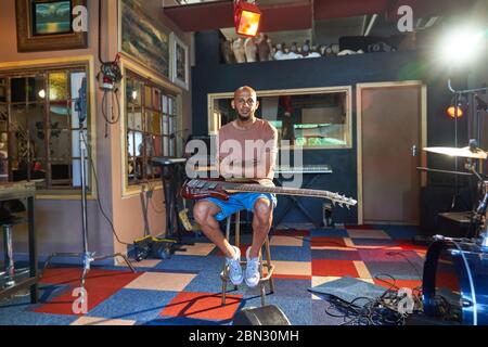 Portrait selbstbewusster männlicher Musiker mit Gitarre im Aufnahmestudio Stockfoto