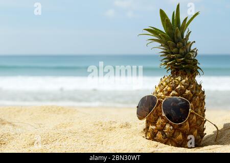 Ananasfrucht und Sonnenbrille am Strand Stockfoto