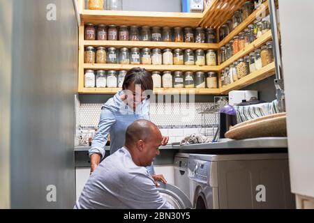 Glückliches Paar, das in der Küche Wäsche macht Stockfoto