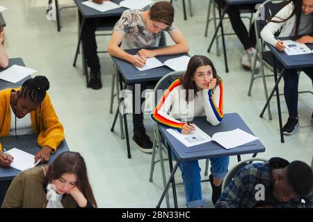 Nachdenklich High School Mädchen unter Prüfung am Schreibtisch im Klassenzimmer Stockfoto