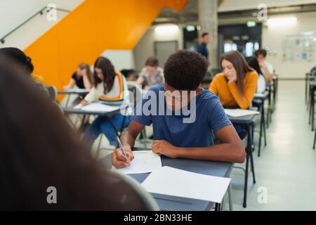 Fokussierte High School Jungen Schüler, die Prüfung am Schreibtisch Stockfoto