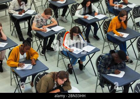 Fokussierte Schüler, die an den Schreibtischen im Klassenzimmer die Prüfung ablegen Stockfoto