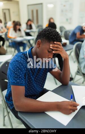 Fokussierte High School Jungen Schüler, die Prüfung am Schreibtisch im Klassenzimmer Stockfoto