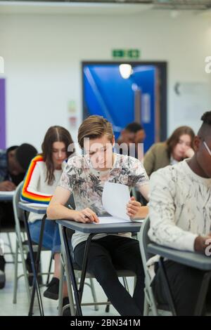 Fokussierte High School Jungen Schüler, die Prüfung am Schreibtisch im Klassenzimmer Stockfoto