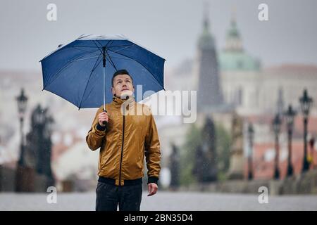 Einsamer Mann mit Regenschirm bei starkem Regen auf der leeren Karlsbrücke. Prag Tschechische Republik Stockfoto
