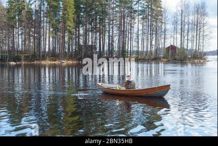 Fischer Trolling von Ruderboot / Schiff am Fluss Nokienkoski, Finnland Stockfoto