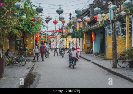 Wundervolle Aussicht auf die alte Straße, die mit bunten Seidenlaternen dekoriert ist. Vietnamesen in traditionellen schließt Spaziergang entlang Hoi an Altstadt. Hoi an (Hoi an), Vietnam - 12. März 2020. Stockfoto