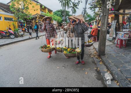 Wundervolle Aussicht auf die alte Straße, die mit bunten Seidenlaternen dekoriert ist. Vietnamesen in traditionellen schließt Spaziergang entlang Hoi an Altstadt. Hoi an (Hoi an), Vietnam - 12. März 2020. Stockfoto