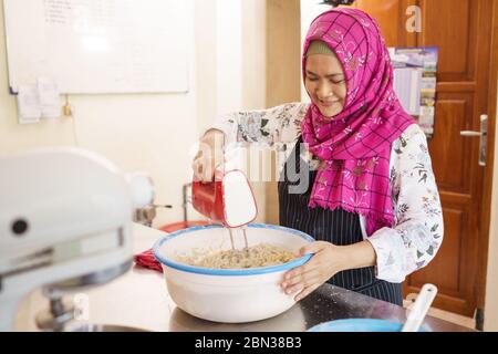 Glücklich muslimische Frau hausgemachte Backen. Bäckerei Besitzer Mischen etwas Teig Stockfoto