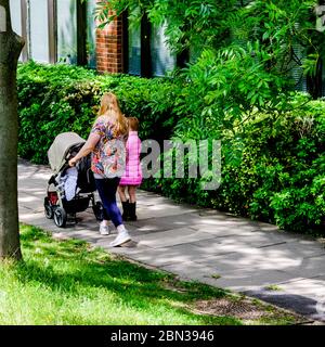 Mutter und Kinder, die ihre tägliche Exzerice allein haben, wie von den Richtlinien der Regierung während des Coronavirus-Ausbruchs empfohlen Stockfoto
