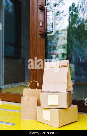 Lieferboxen, Papiertüten vor der Haustür in der Nähe der Haustür. Kontaktlose Lieferung. Sicheres Einkaufen E-Commerce Kauf Pakete nach Hause. Boxen geliefert an Stockfoto