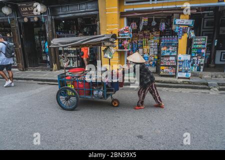 Wundervolle Aussicht auf die alte Straße, die mit bunten Seidenlaternen dekoriert ist. Vietnamesen in traditionellen schließt Spaziergang entlang Hoi an Altstadt. Hoi an (Hoi an), Vietnam - 12. März 2020. Stockfoto