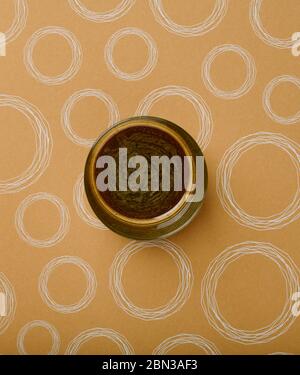 Schwarzer Kaffee mit Sahne in einer transparenten Tasse in der Mitte eines braunen Hintergrunds wie Creme mit scharfen weißen Kreisen Stockfoto