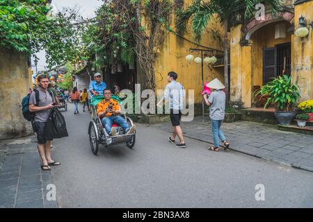 Wundervolle Aussicht auf die alte Straße, die mit bunten Seidenlaternen dekoriert ist. Vietnamesen in traditionellen schließt Spaziergang entlang Hoi an Altstadt. Hoi an (Hoi an), Vietnam - 12. März 2020. Stockfoto