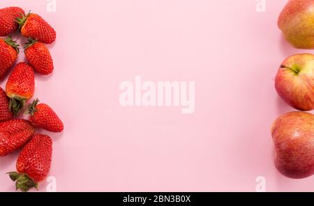 Erdbeeren und Äpfel auf einem rosa Hintergrund. Mit Kopierraum für Ihren Text. Stockfoto