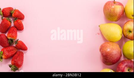 Erdbeerbirnen und Äpfel auf rosa Hintergrund. Stockfoto