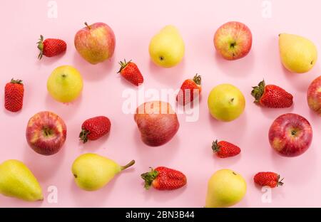 Erdbeerbirnen und Äpfel auf rosa Hintergrund. Stockfoto