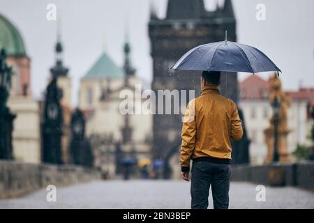 Einsamer Mann mit Regenschirm bei starkem Regen auf der leeren Karlsbrücke. Prag Tschechische Republik Stockfoto
