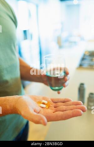 Nahaufnahme Mann unter Vitaminen und Ergänzungen mit einem Glas Wasser Stockfoto