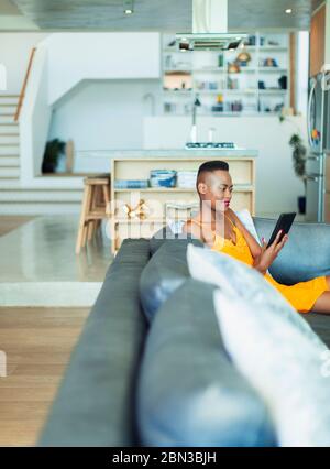 Junge Frau mit digitalen Tablet auf dem Sofa im Wohnzimmer Stockfoto