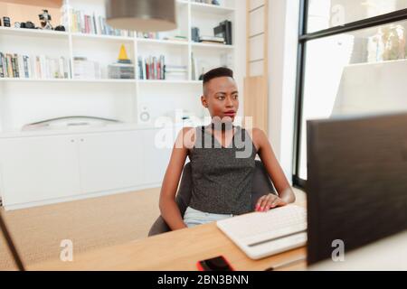 Junge Frau, die von zu Hause aus arbeitet, Computer im Büro benutzt Stockfoto