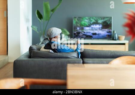Mann, der auf dem Sofa im Wohnzimmer Fernsehen sah Stockfoto