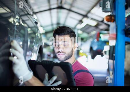 Fokussierte männliche Mechaniker mit digitalen Tablet in der Auto-Werkstatt Stockfoto